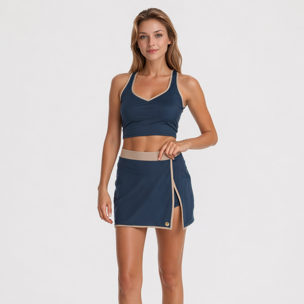Woman wearing a navy sports bra and skirt on a white background