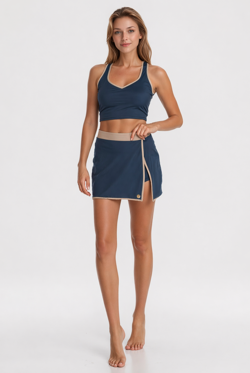 Woman wearing a navy sports bra and skirt on a white background