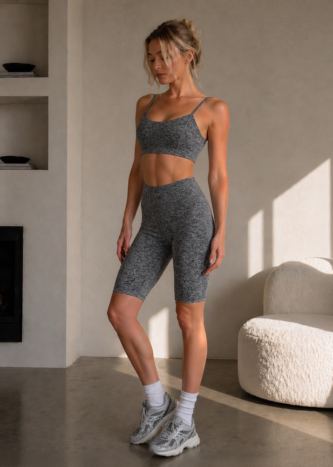 Woman in gray athletic wear standing in a modern room with neutral decor.
