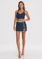 Woman wearing a navy sports bra and skirt on a white background
